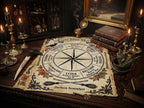 A decorative occult-style whee of the year calendar  laid out on a dark wooden table, surrounded by candles, books, a mirror, and other gothic props. The central printed disc shows seasonal and lunar markers with ornate black illustrations and text on aged cream paper.