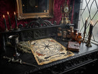 A gothic-style altar scene featuring a central Wheel of the Year parchment page on a dark carved wooden table, surrounded by candles, apothecary bottles, a dagger, dried herbs, and an old book, set against a dark red damask wall.