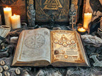 Open book with magical symbols and illustrations on a table with candles and figurines.