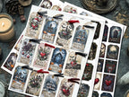 A styled flat-lay of multiple sheets of gothic christmas-themed printable tags or stickers, each with a different illustrated label such as 'Gothic Angel,' 'Haunted Holidays,' 'Winter Gothic,' and 'Deadly Romance.' The sheets are arranged on a dark textured surface with candles, a pinecone, and other moody props around them.