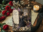 Moody product photo of a vintage-inspired gothic journal page with candle snuffer artwork, red roses, a lit pillar candle, black lace, wax seals, and layered antique parchment on a rustic wood surface.