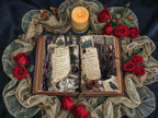 Open gothic-style vintage journal spread with spellbook-inspired pages, surrounded by red roses, dried flowers, and a lit candle for a moody Victorian look.