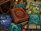 A styled tabletop arrangement of fantasy Gods of the Necronomicon pages, including a central red hardcover book titled Necromancer, several illustrated pages with teal, blue, and fiery artwork, a chain, and open books in a moody setting.