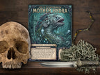 A tabletop product display featuring a fantasy page titled "Gods of the Neironomicon: Mother Hydra," surrounded by a human skull, a silver dagger, and a bundle of dried moss on a dark wood surface.