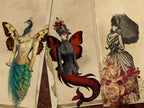 Three vintage-style illustrated prints arranged overlapping on a textured beige surface. The left illustration shows a woman with a peacock head and butterfly wings in a teal and gold dress.