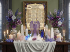 Decorative altar with angel statue, candles, and flowers against a wall with an angel chart.