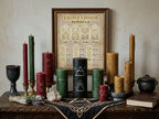Collection of candles and a framed candle carving symbols poster on a witch's altar with a neutral background